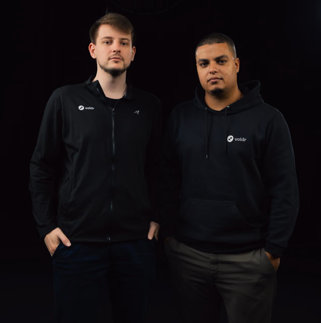 Two people wearing Voidr jackets against a dark background.