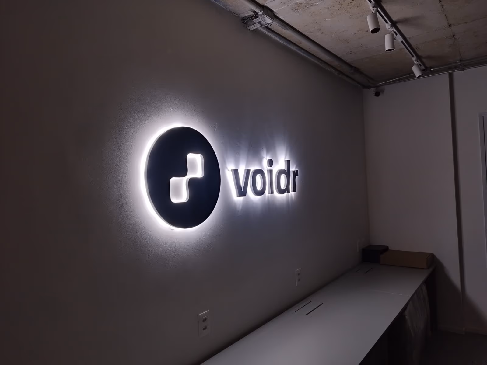 The illuminated Voidr logo on the office wall.